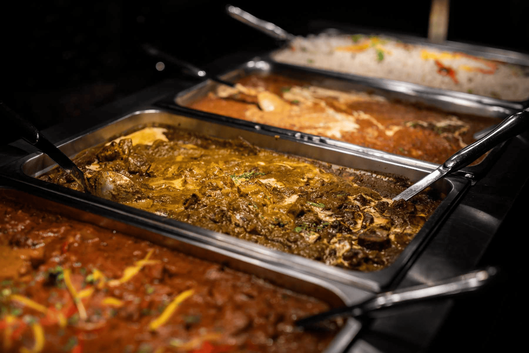 A plate of Indian food with rice, curry and naan bread served in a catering tray